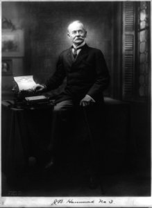 J.B. Hammond, full length portrait, seated on table, facing front; with typewriter LCCN2005686701 photo