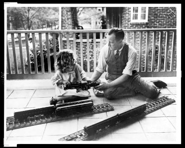 J.N. Swartzell and daughter Margaret seated with parts of electric train, on porch of home, Washington, D.C. LCCN99471538