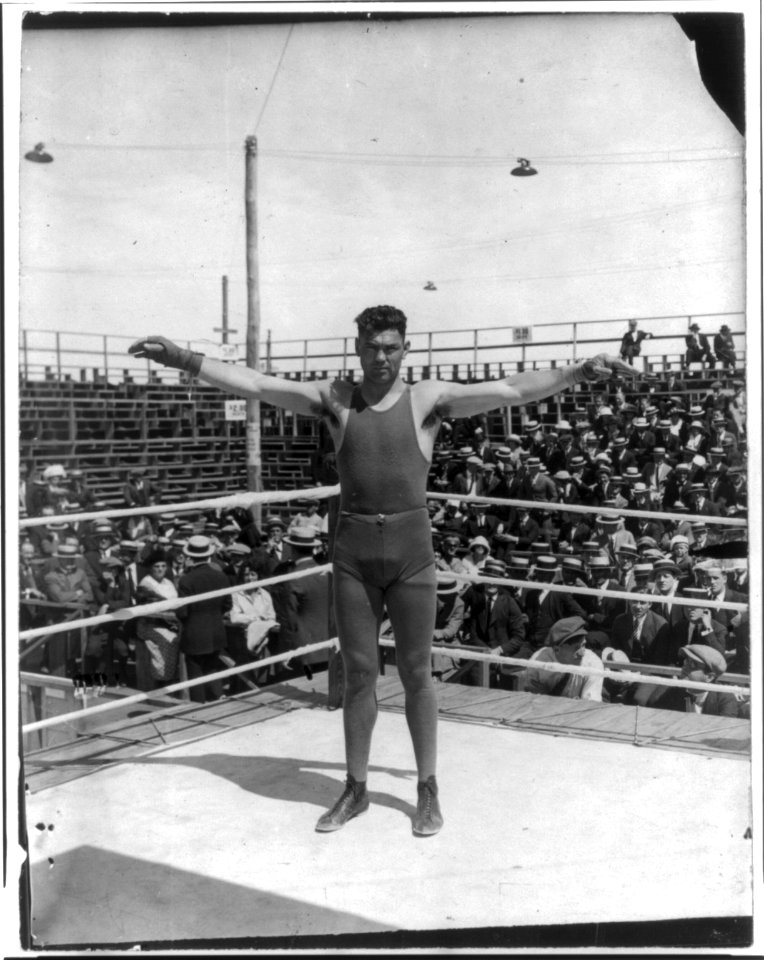 Jack Dempsey at his training camp, June 1921- standing in ring with arms spread wide LCCN2005681074