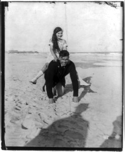 Jack Dempsey at his training camp, June 1921- kneeling on beach, with small girl piggyback LCCN2005681061