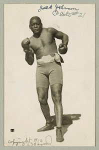 Jack Johnson, full-length portrait, standing facing front, wearing boxing shorts and boxing gloves LCCN93511535