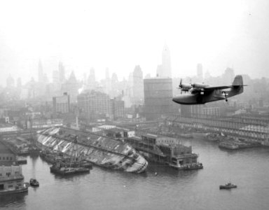J4F Widgeon flies over wreck of Lafayette in New York 1943