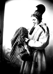 Kvinne i sameliknende drakt med kofte, hornlue og komse. Nålehus med beltering - Norsk folkemuseum - NF.25780-844