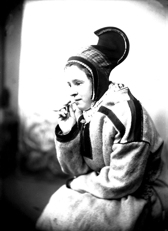 Kvinne i sameliknende drakt med kofte, hornlue og pipe - Norsk folkemuseum - NF.25780-842