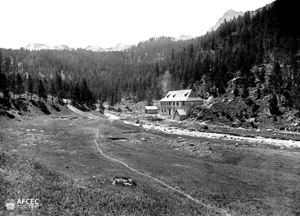 L'edifici dels banys de Tredòs amb el riu Aiguamòg al davant i al fons bosc i muntanyes