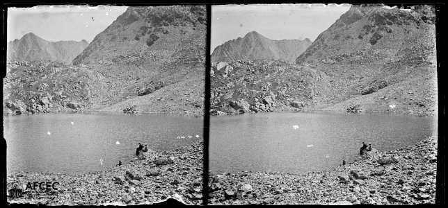 L'estany Blau amb algunes persones a la riba i al fons el pic de l'Infern