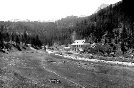 L'edifici dels banys de Tredòs amb el riu Aiguamòg al davant i al fons bosc i muntanyes (cropped)