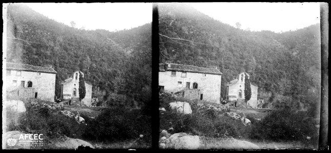 L'ermita de Sant Aniol d'Aguja amb un edifici al costat i algunes persones al davant