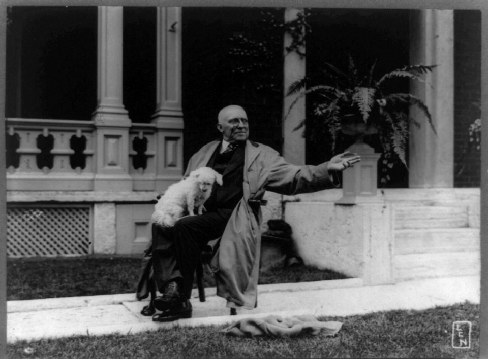 James Whitcomb Riley, full-length portrait, seated, facing right, with dog upon his lap, waving goodbye, on sidewalk in front of porch) - LCN LCCN89710629