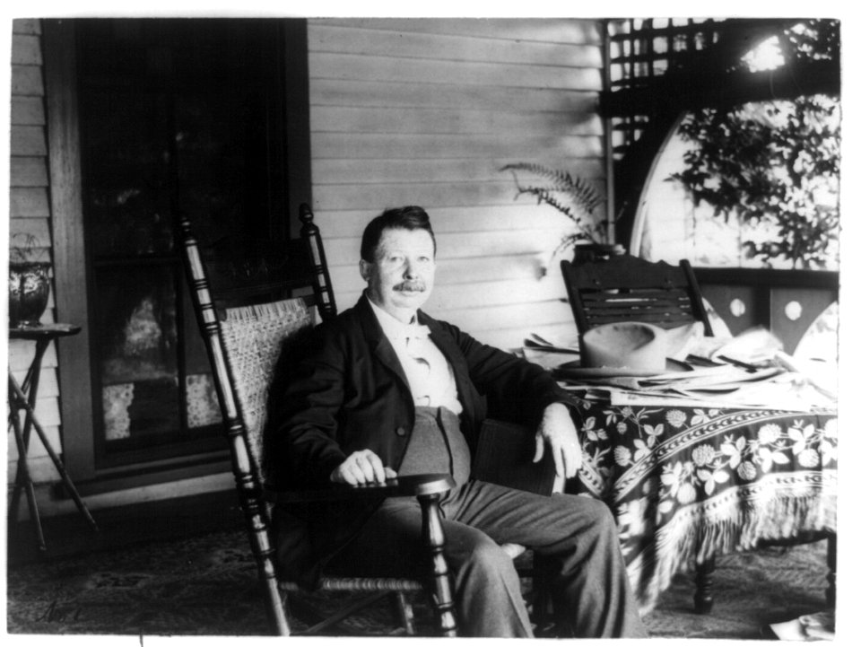 Joel Chandler Harris, three-quarter length portrait, seated at table on porch of his home, facing slightly right LCCN2003653784
