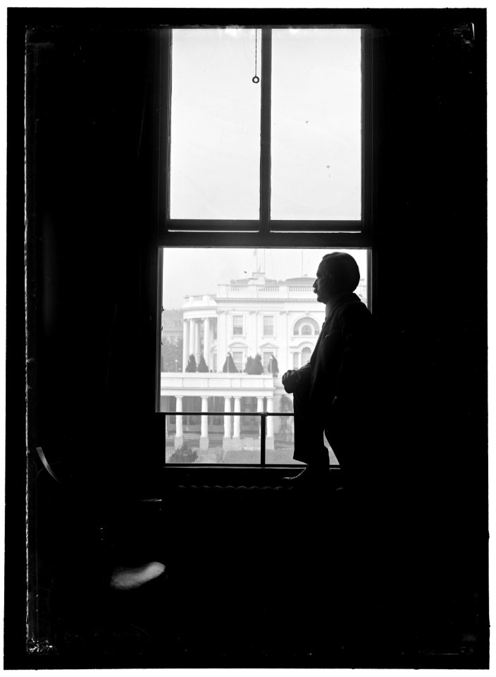 John Skelton Williams at window with White House visible in background, Washington, D.C. LOC hec.10267