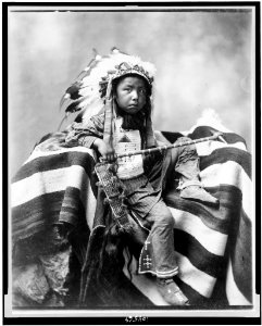 Joseph Bird Head, Lakota or Sioux, full-length portrait, seated on blanket holding handcrafted club, facing slightly right LCCN91481296
