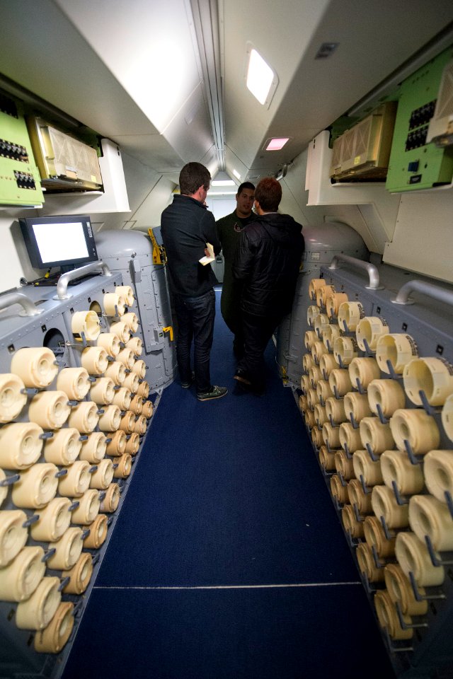 Jon Donnison, left, a journalist with BBC News, and Nicolas Perpitch, right, a journalist with The Australian, speak with U.S. Navy Naval Aircrewman (Operator) 2nd Class Julio Cerpa, assigned to Patrol 140404-N-VD564-045