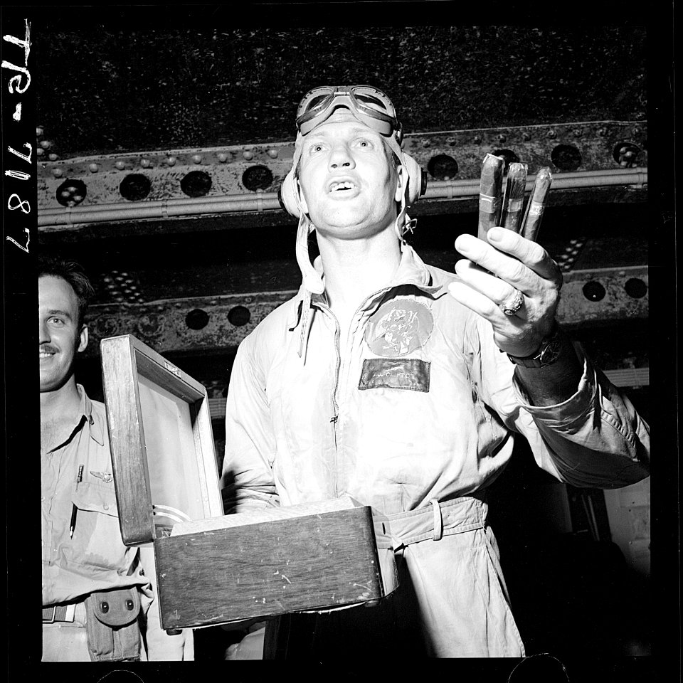 Jubilant over the success of the task force raid on Rabaul, Cdr. Joseph C. Clifton passes out cigars aboard USS... - NARA - 520765