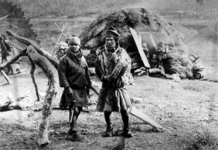 Karesuando-samer på sommeropphold i Lyngseidet. To samer i forgrunnen, gamme i bakgrunnen. Ca - Norsk folkemuseum - NF.09881-003