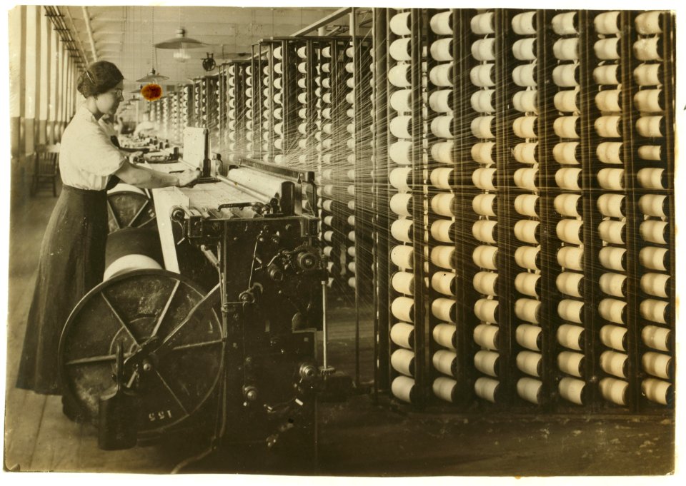 King Philip - Spool and Warping Department. Warper - Young girls sometimes assist. Sometimes a tyer-in comes from her position behind the rack and helps the warper. Light very good in this LOC cph.3b33428