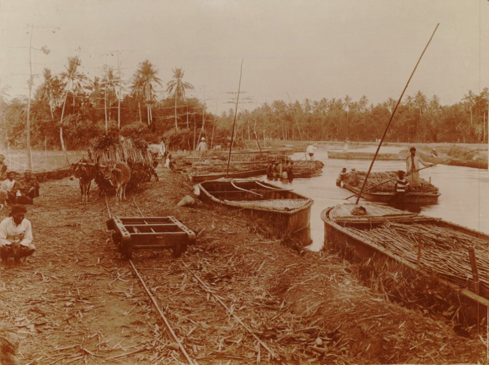 KITLV - 152200 - Kurkdjian - Loading boats with sugarcane from trucks at a sugar company in the Dutch East Indies - 1921