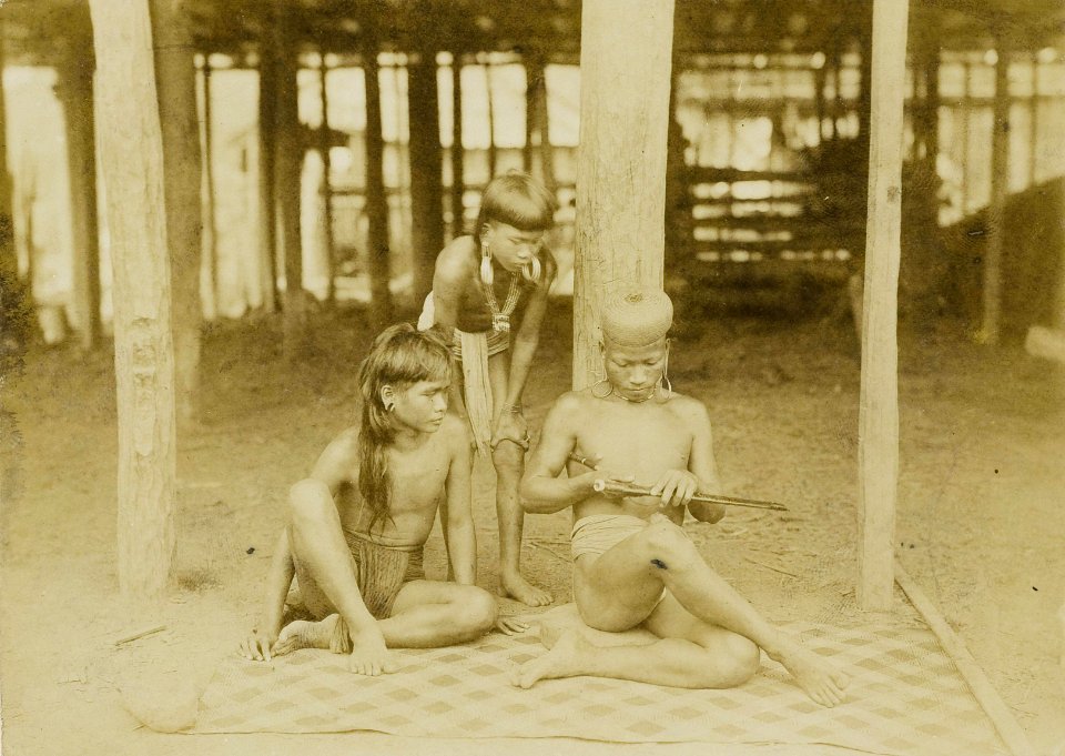 KITLV - 160460 - Demmeni, J. - Soelang Orang makes a wood carving on a sword scabbard with a long sharp knife that the Bahau people carry on the inside of their swords, Upper Mahakam - 1898-1900