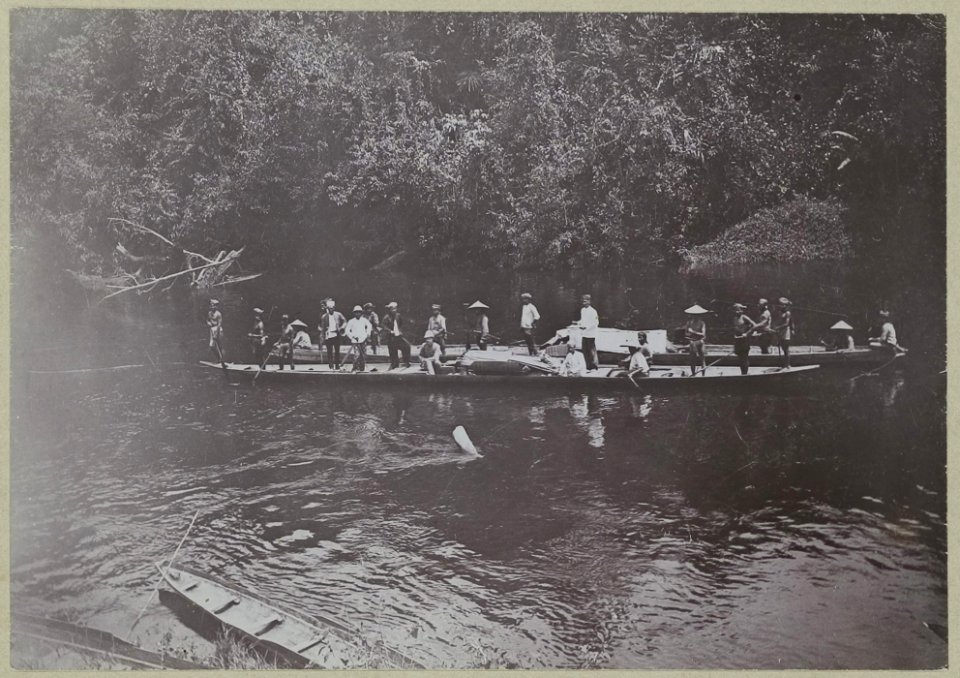 KITLV - 25670 - Demmeni, J. - Return of the ambassy of the Lower Mahakam in two boats on the Bloeoe River, Central Borneo. Sitting on the front boot (with topi helmet) Dr. A. W. Nieuwenhuis - 1896-1897