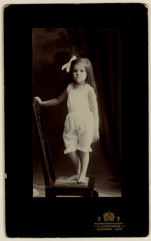 KITLV - 28995 - Kurkdjian, N.V. Photografisch Atelier O. - Soerabaja - European girl standing on a chair in the studio of O. Kurkdjian, Surabaya - circa 1900