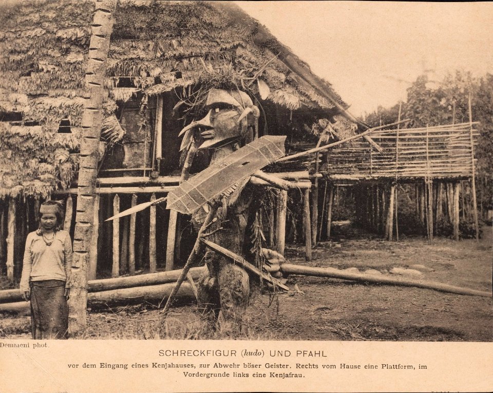 KITLV - 173522 - Demmeni, J. - Kenyah woman standing next to a defense post and statue on Borneo - 1890-1904