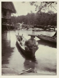 KITLV - 26474 - Kurkdjian - Soerabaja - Woman with child in a small boat near a river bank - circa 1905