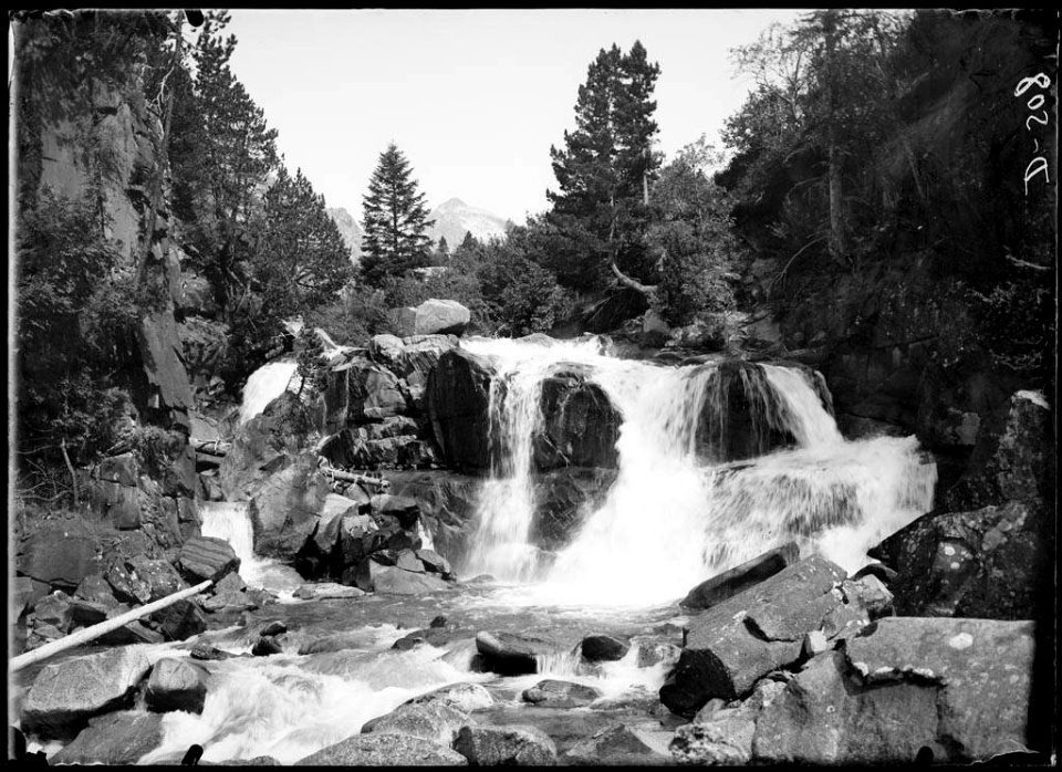 La cascada de San Farré en una vall boscosa amb muntanyes al fons (AFCEC SOLER D 0508)