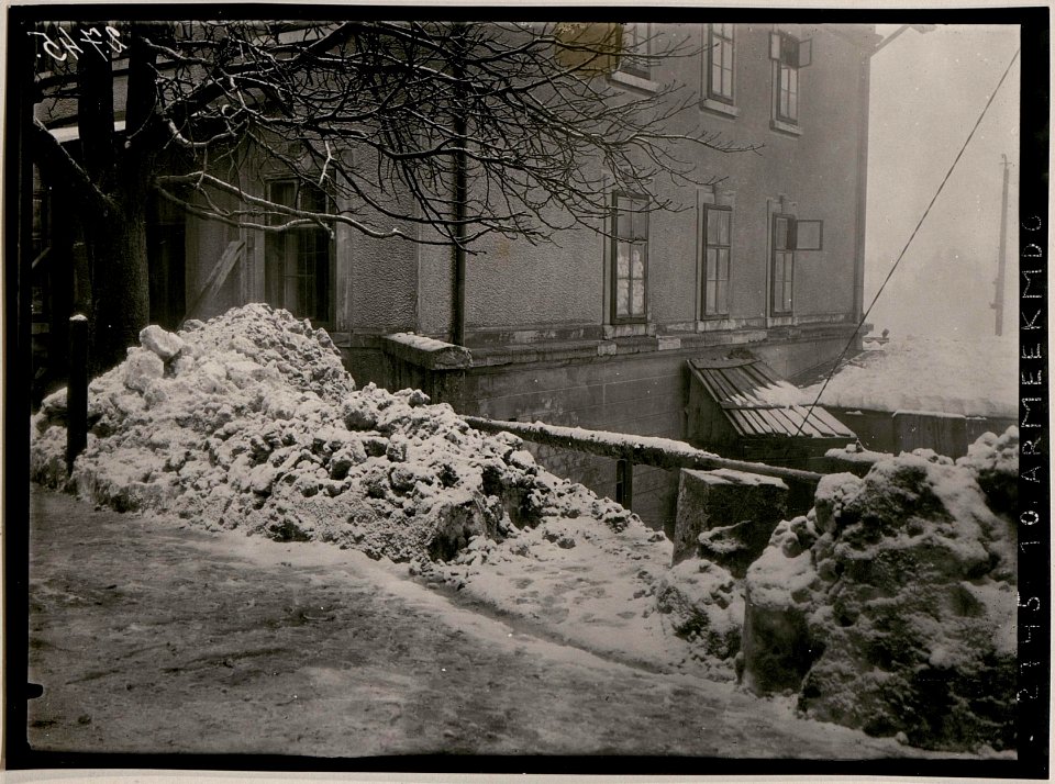 Lawine in Tarvis. Die Lawine staute sich an die Bahnhofsgebäudemauer und stürzte mit der Strassenrampe (Stützmauer) hinunter zur Feldpost, wo sie liegen blieb (BildID 15731198)