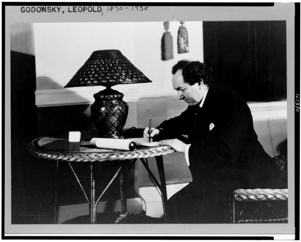 Leopold Godowsky, three-quarter length portrait, seated at rattan table with lamp, facing left, writing LCCN92510603
