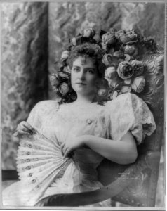 Lillian Russell, 1861-1922, half length portrait, seated in chair, flowers around head, holding fan, facing slightly left LCCN2005692229