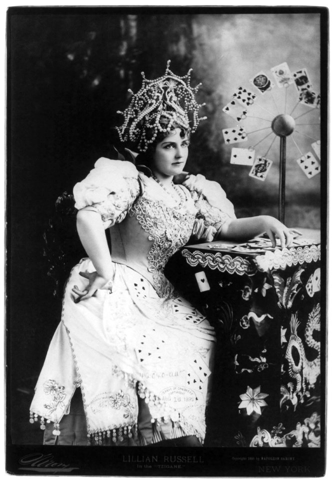 Lillian Russell, 1861-1922, three-quarters length, seated, facing right; with cards at table, in the Tzigane (fortune teller) LCCN2007675572