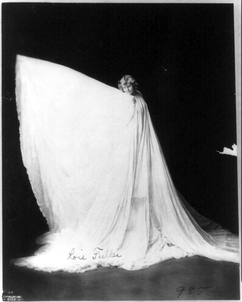 Loie Fuller, d. 1928, full length, standing, facing left, wearing gown, with elongated right arm extension LCCN2005685074