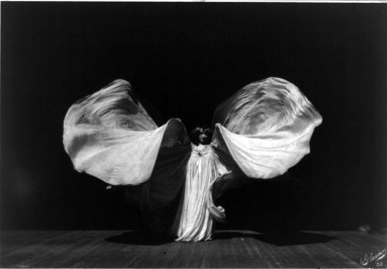 Loie Fuller, full-length portrait, standing, facing front; raising her very long gown in shape of butterfly LCCN96514367