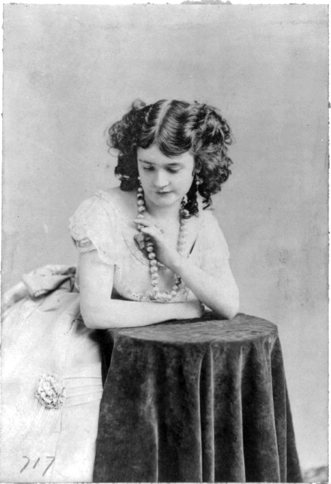Lotta Crabtree, half-length portrait, facing left, leaning on table, looking down LCCN2005690004