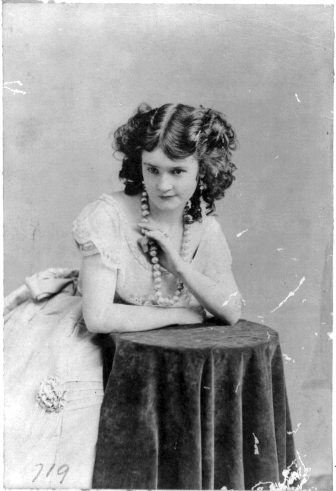 Lotta Crabtree, half-length portrait, facing left, leaning on table, looking up LCCN2005690005