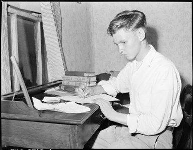 Louis Sergent, 16, who is in his first year at high school, does his homework. Both he and his father are determined... - NARA - 541288 photo