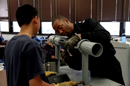 Machinist's Mate 1st Class Marteaus Dykes shows a student from Mira Mesa High School Air Force Junior Reserve Officer Training Corps (JROTC) how to patch pipe photo