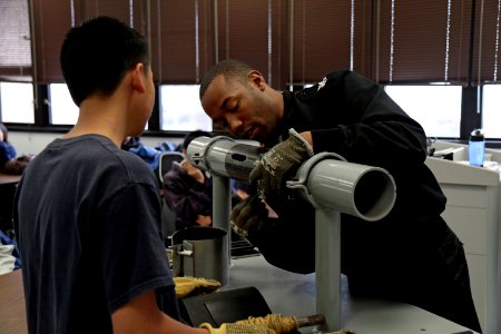 Machinist's Mate 1st Class Marteaus Dykes shows a student from Mira Mesa High School Air Force Junior Reserve Officer Training Corps (JROTC) how to patch pipe