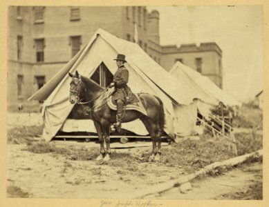 Major-General Joseph Hooker, full-length portrait, seated on horse, facing left, wearing military uniform, two tents and large building in the background LCCN2008680203