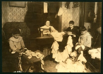 Making dresses for Campbell Kid Dolls in a dirty tenement room, 59 Thompson St., N.Y. 4th floor front. Romana family. The older boy, about 12 years old, operates the machine when the mother LOC nclc.05492