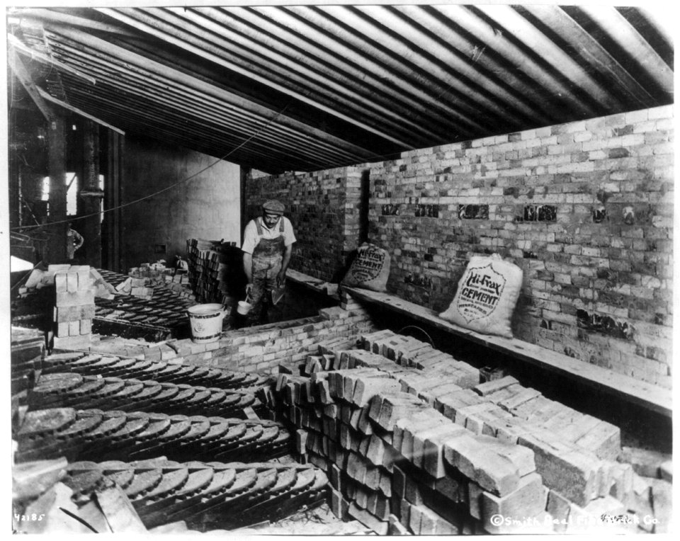Man laying bricks inside building LCCN2002699603