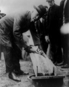 Man pouring two bottles of beer into trough into the sewer system during Prohibition in 1921, detail, from- Zion City, Ill., destroys 80,000 pint bottles of beer LCCN88715937 (cropped) photo