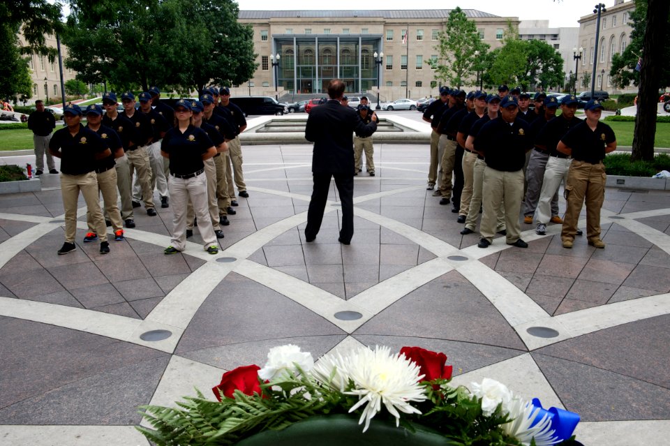 Man speaks to law enforcement explorers at National Law Enforcement Officers Memorial with wreath