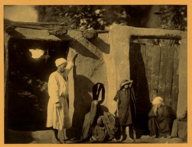 Man, woman, and children outside earth and wood structure LCCN2004674237