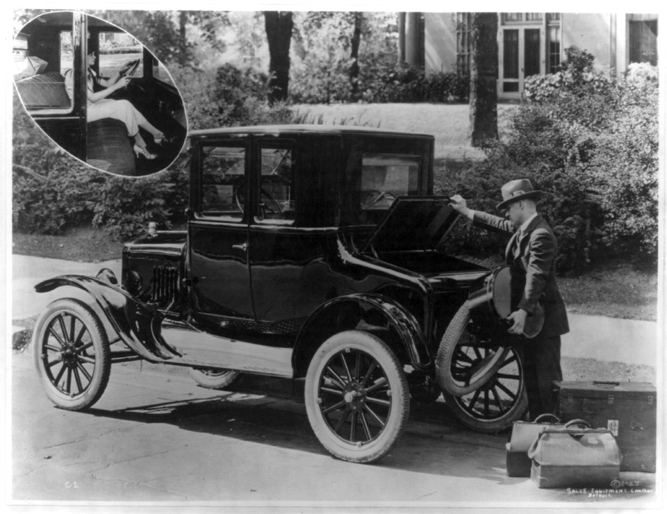 Man loading luggage into the trunk of a Ford coupe; insert of a woman seated behind steering wheel LCCN95500814
