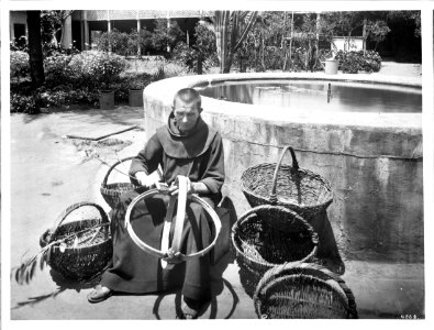 Monk sitting making baskets near the fountain in the garden at Mission Santa Barbara, ca.1898-1901 (CHS-4068)
