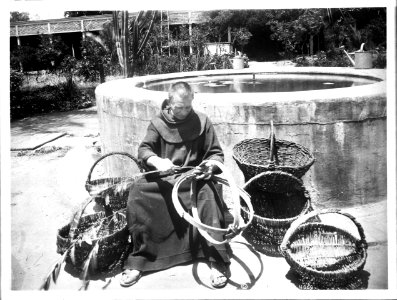 Monk sitting making baskets near the fountain in the garden at Mission Santa Barbara, ca.1898-1901 (CHS-4069)