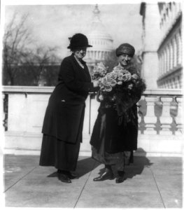Miss Alice Robertson of Okla. presenting her new collegue (sic), Mrs. Winifred Mason Huck with flowers on the latter's arrival at the House Office Building LCCN2002695662