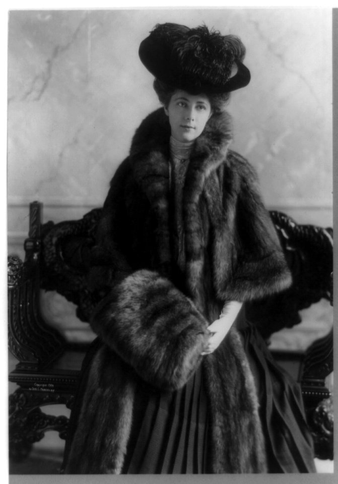 Miss A. L. Ide, three-quarter-length portrait, standing, facing right, wearing fur coat, plumed hat and muff LCCN91481430