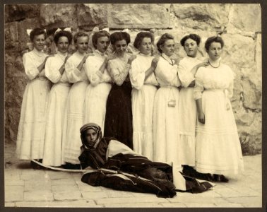 Nine girls standing over young boy holding sword and dressed in traditional Bedouin clothing LCCN2007682802
